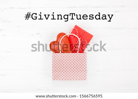 Giving Tuesday is a global day of charitable giving after Black Friday shopping day. Charity, give help, donations and support concept with text message, red heart and gift in shopping bag