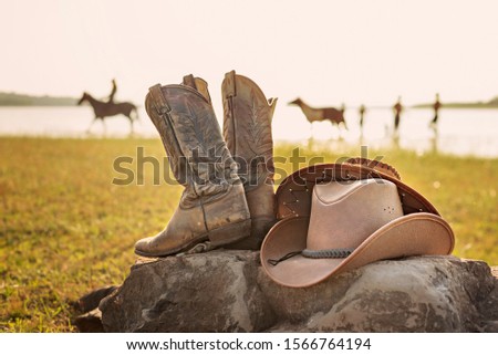 Wild West retro cowboy hat and pair of old leather boots on the rock