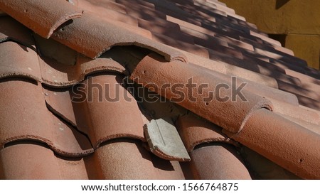 Broken roof tile in need of repair                                Royalty-Free Stock Photo #1566764875