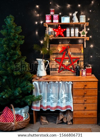 Interior wooden rustic kitchen on black background and red Christmas decor. Cooking a festive dinner at home in the kitchen concept. The new year 2020. Shelves with lights garlands and festive dishes.