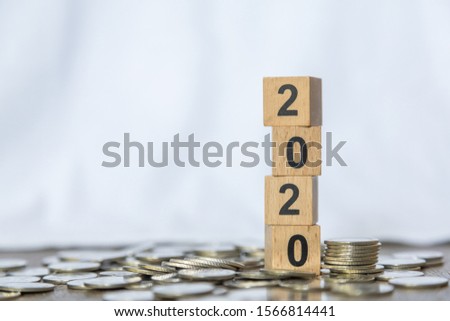 2010 New year, Money and Business Concept. Close up of stack of number wooden block toy on pile of coins white background.