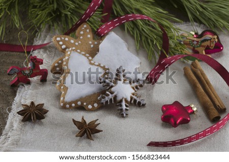 Christmas card: gingerbread cookies in the form of Christmas trees and snowflakes, anise, cinnamon sticks, red Christmas tree decorations, pine needles, red ribbon