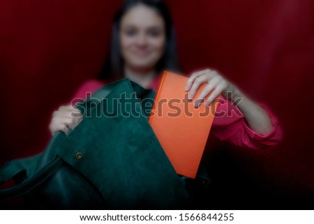 photo of a young beautiful girl with dark hair; a young girl holding a book of books and a green backpack; studio photography; blur 