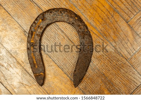 Old destroyed and rusty horse horseshoe on a wooden background. A symbol of happiness and good luck.