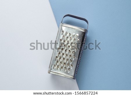 Old metal grater on a colored paper background. Top view. Studio shot