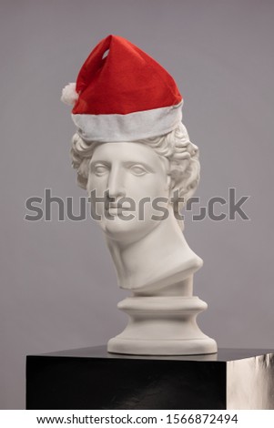 Statue of a bust of Apollo Belvedere in a red hat of Santa Claus