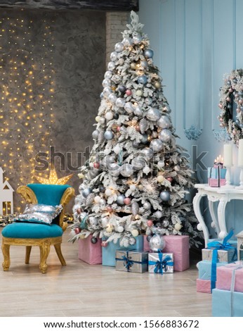 Christmas tree with blue and pink gifts in the white room Christmas. Beautifully decorated house with a silver, pink and blue tree and presents at Christmas.