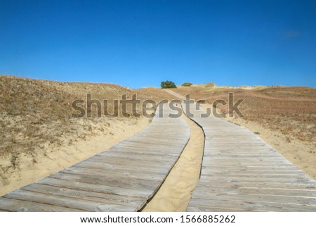 A picture from the Curonian Spit (Kursiu Nerija) National Park in Lithuania. The wooden tourist path climbing to the top of the sand dune. 