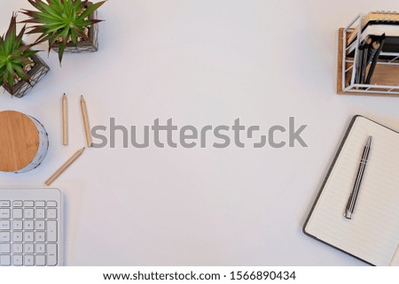 Notebook and pen on white office table with copy space. Desktop with wooden pencils, keyboard and succulent with blank space for your text.