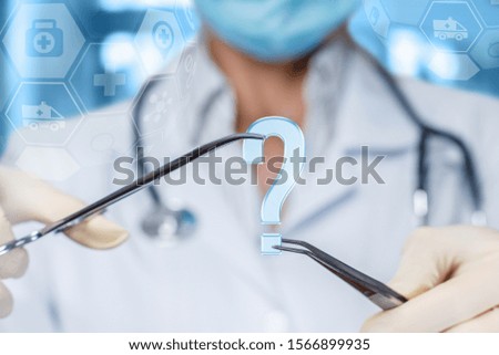 Concept questions and answers in surgery. Doctor shows a question mark on blurred background.