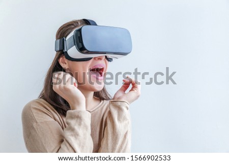 Smile young woman wearing using virtual reality VR glasses helmet headset on white background. Smartphone using with virtual reality goggles. Technology, simulation, hi-tech, videogame concept