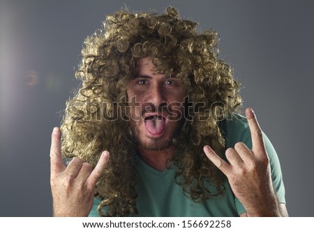Portrait of a guy with a wig doing a rock and roll symbol 