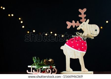 A small wooden deer stands on a table with miniature sleigh. Fairytale Christmas atmosphere