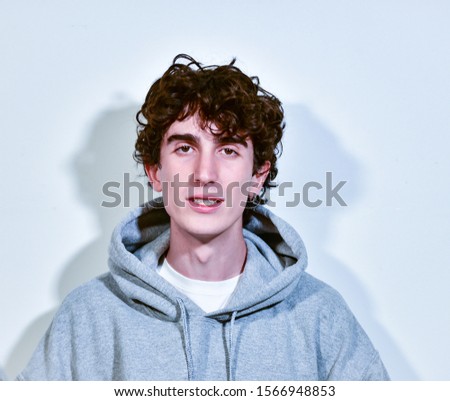 expressive italian teenager model boy with dark hair posing for a casual fashion shooting wearing a hood