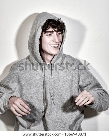 expressive italian teenager model boy with dark hair posing for a casual fashion shooting wearing a hood