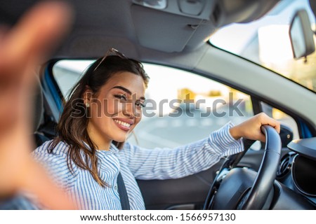 Smiling young woman taking selfie picture with camera in car. Holidays and tourism concept - smiling teenage girl taking selfie picture in car. Beautiful young woman in car, taking selfie