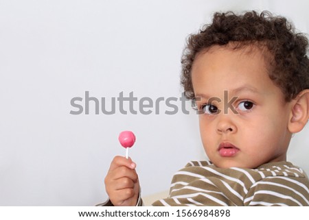 little boy licking a sweet lollipop on grey background stock photography stock photo