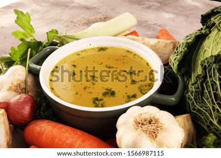 Broth with carrots, onions various fresh vegetables in a pot - colorful fresh clear spring soup. Rural kitchen scenery vegetarian bouillon