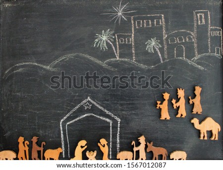 wooden figures on a chalk drawing of a christmas nativity scene