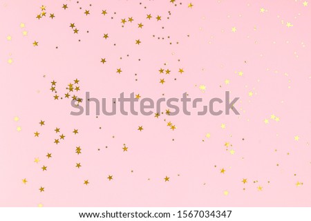 Golden stars glitter confetti in abstract style on pink background. Gold sparkles texture. Holiday new year backdrop. Anniversary, birthday. Greeting card template. Royalty-Free Stock Photo #1567034347