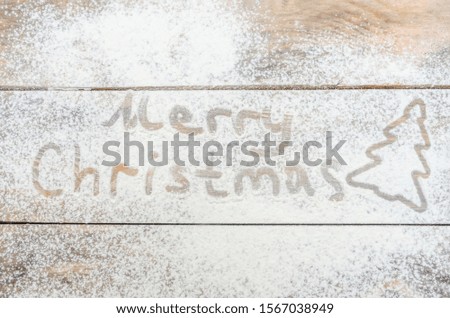 Merry Christmas-Christmas background with white flour and silhouette of Christmas tree with inscription. The view from the top .