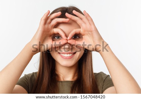 Close up portrait of cheerful, cute, stylish,attractive, trendy girl making binoculars with fingers, isolated on grey background, having good mood