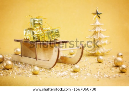 Wooden christmas sleigh carrying many presents, surrounded by gold decoration