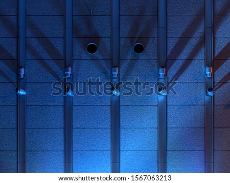 Background image of a rough textured wall made of concrete, lightly lit by a blue spotlight