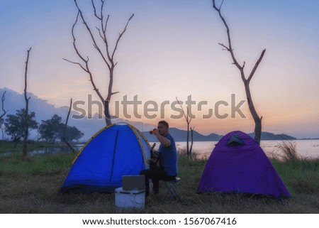 Two Asian men had fun camping in the river at sunset.