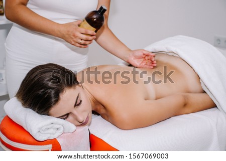 Young woman having a massage. Masseur applying scented oil