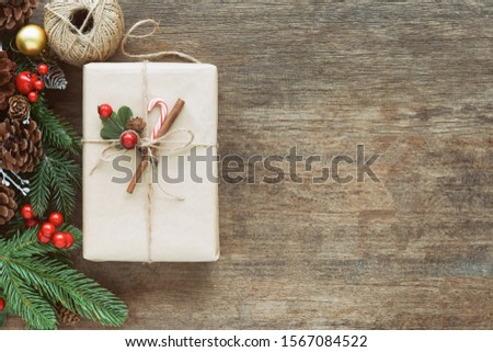 Wood table plank decorate with pine leaves and pine cones, holly balls, ball or bauble and gift box in Christmas concept. Background in top view flat lay with copy space for Christmas wallpaper