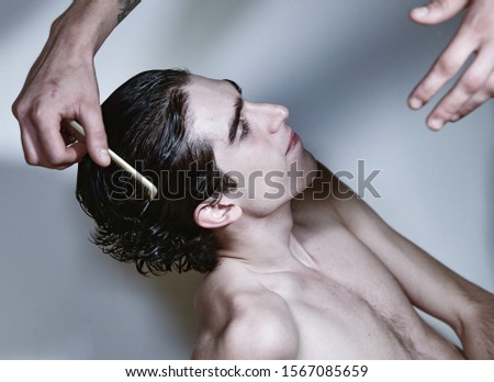 portrait photography. young handsome Italian teenager model boy with angel face and dark hair posing for fashion shooting and getting his hair styled. white background