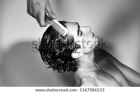 black and white photography. portrait of young handsome Italian teenager model boy with dark hair and angel face posing for a fashion shooting and getting his hair styled