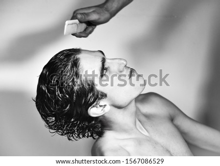 black and white photography. portrait of young handsome Italian teenager model boy with dark hair and angel face posing for a fashion shooting and getting his hair styled