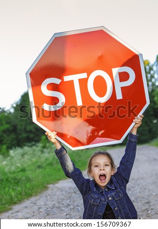 Beautiful little girl screaming and holding red sign "STOP".