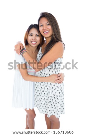 Two sweet sisters hugging each other on white background