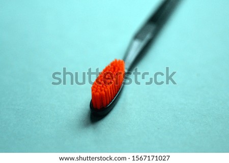 Black toothbrush on a blue background. Black brush with orange bristles. Clean teeth. Health. Anti caries. Oral care item.