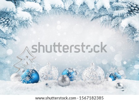 Merry Christmas background. Blue christmas balls and baubles and wooden decorative tree on the snow with fir branches. Mixed media.