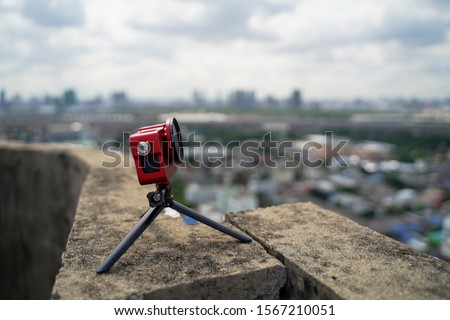 Action camera attached with camera stand recording video or taking a photo with blurred city background.  