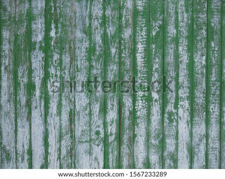 the texture of an old fence with vertical boards and painted green, but it has faded and the paint has peeled off from time