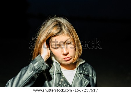 cute young dark-haired girl looking down, straightening hair with hands in the dark