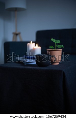 Cozy atmosphere, warm house. Candle, coffee, book, flower. Dark Photo Style