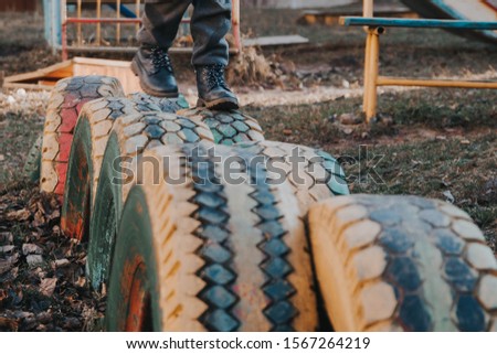 The Playground is made of old car tires. Tires, wheels painted with colorful paints. The child runs on the tires dug into the ground. Fun game.