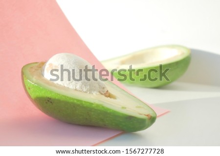 Avocado cut in half on white and pink background. Copy space. Banner. Background for eco cosmetics.
