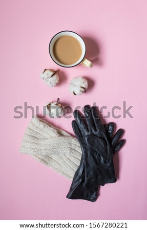 Creative flat lay. Gloves and headband 
with cotton flowers and coffee cup on pink background. Winter girly gifts concept for Christmas, stylish woman or lifestyle blog. Top view, copy space.