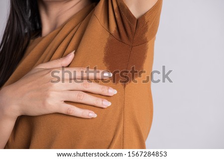 Close-up asian woman with hyperhidrosis sweating. Young asia woman with sweat stain on her clothes against grey background. Healthcare concept. Royalty-Free Stock Photo #1567284853