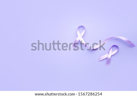 Lilac ribbons on color background. Cancer awareness concept