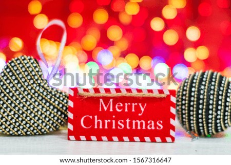 Merry Christmas wooden sign. Christmas composition on blurred lights background. Colorful Christmas balls.