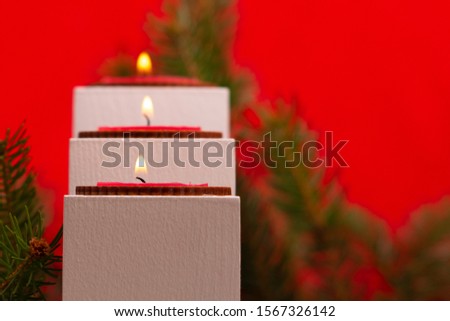 Christmas , white candles and spruce on a red background
