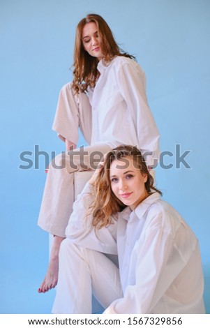 two girls in white clothes pose on a blue background